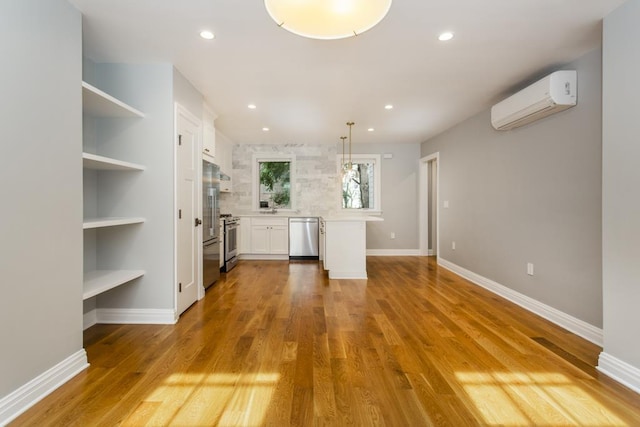 interior space with white cabinetry, light countertops, stainless steel appliances, and a wall mounted AC