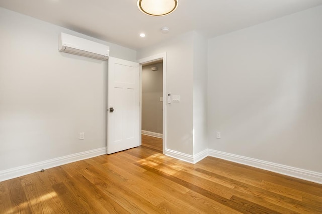 unfurnished room featuring an AC wall unit, recessed lighting, baseboards, and light wood finished floors