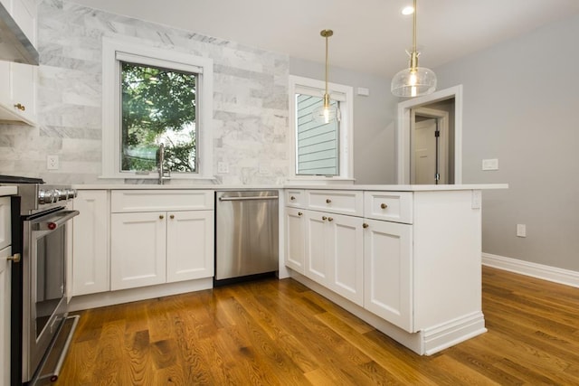 kitchen featuring dark wood-type flooring, appliances with stainless steel finishes, a peninsula, exhaust hood, and white cabinets