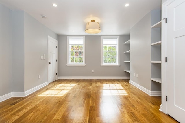 unfurnished room featuring built in features, recessed lighting, light wood-type flooring, and baseboards