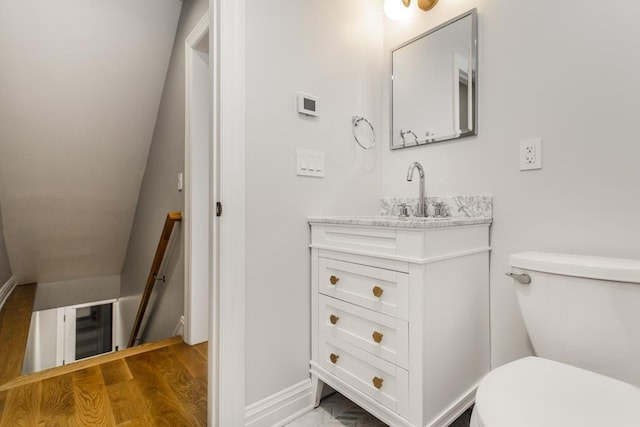 bathroom featuring baseboards, toilet, wood finished floors, and vanity