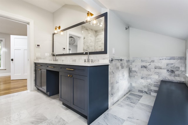 bathroom featuring a sink, lofted ceiling, tile walls, and double vanity