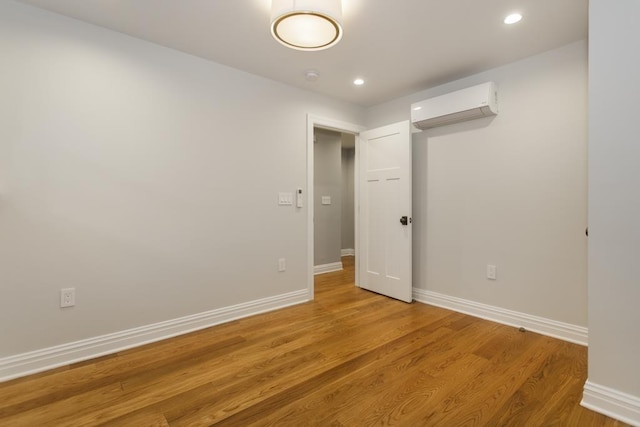 empty room featuring light wood-style flooring, recessed lighting, baseboards, and a wall mounted AC