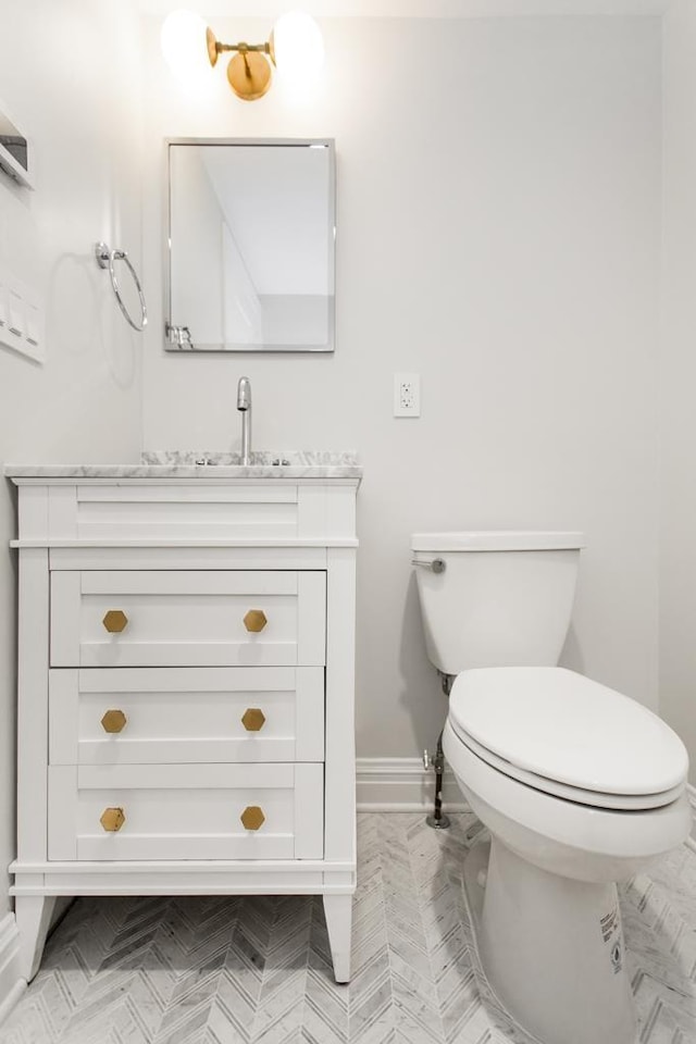 bathroom featuring toilet, vanity, and baseboards