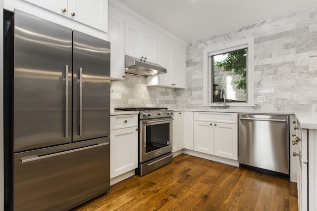 kitchen featuring under cabinet range hood, white cabinetry, light countertops, decorative backsplash, and high end appliances