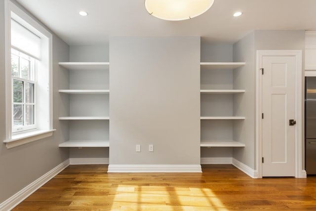 unfurnished bedroom with recessed lighting, wood finished floors, baseboards, and stainless steel built in fridge