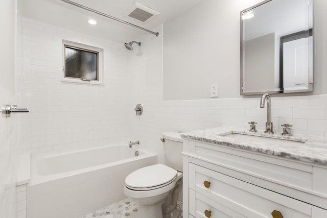 bathroom featuring visible vents, toilet, vanity, shower / bathtub combination, and tile walls