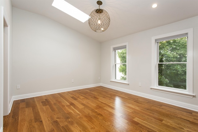 spare room featuring recessed lighting, baseboards, wood finished floors, and lofted ceiling with skylight