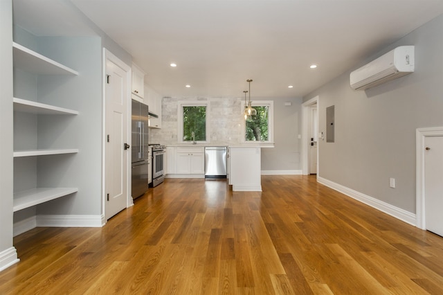 kitchen featuring white cabinets, high end appliances, a wall unit AC, and wood finished floors