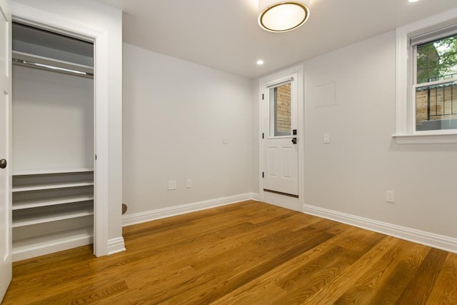 unfurnished bedroom with a closet, recessed lighting, baseboards, and wood finished floors