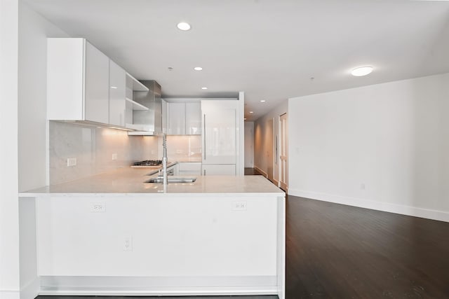 kitchen with a peninsula, backsplash, white cabinets, dark wood-type flooring, and modern cabinets