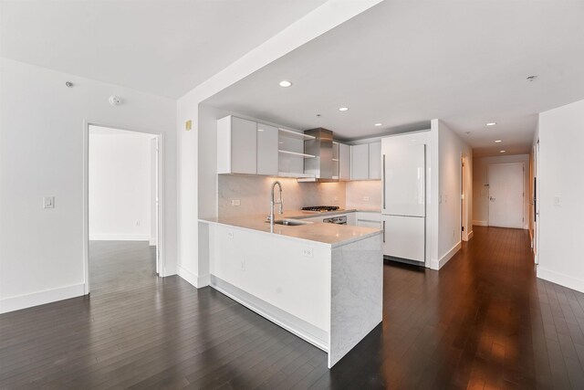 kitchen featuring tasteful backsplash, a peninsula, open shelves, light countertops, and a sink