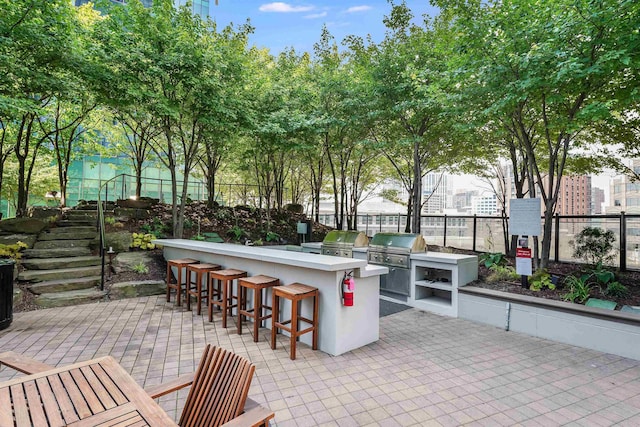 view of patio featuring area for grilling, outdoor wet bar, fence, and a grill