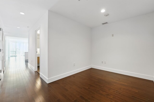 spare room with dark wood-style flooring, visible vents, baseboards, and recessed lighting