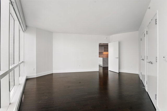 unfurnished room featuring baseboards and dark wood-style floors