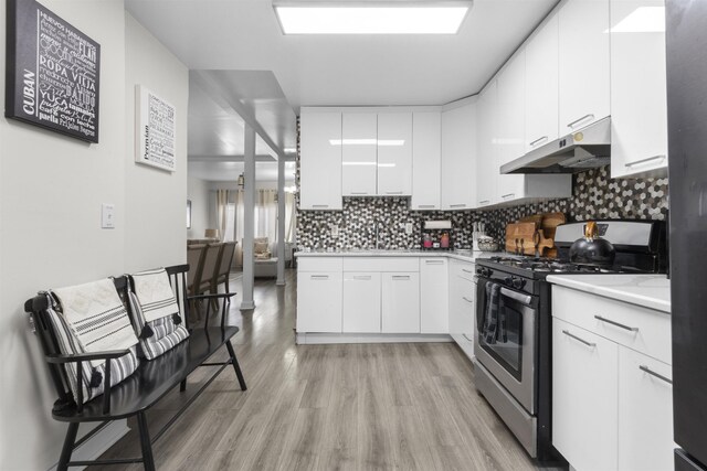 4319 Cottage Ave, North Bergen, NJ 07047 - kitchen featuring gas stove, under cabinet range hood, light countertops, decorative backsplash, and light wood-style floors