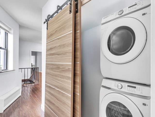 294 Barrow St Unit 6, Jersey City, NJ 07302 - washroom with stacked washing machine and dryer, a barn door, and wood finished floors