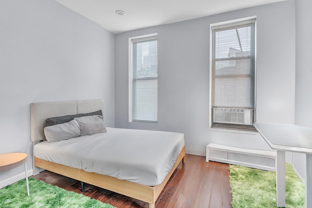294 Barrow St Unit 6, Jersey City, NJ 07302 - bedroom featuring radiator, multiple windows, wood finished floors, and cooling unit