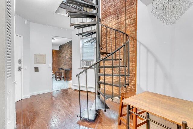 294 Barrow St Unit 6, Jersey City, NJ 07302 - stairway featuring brick wall, a chandelier, and hardwood / wood-style floors