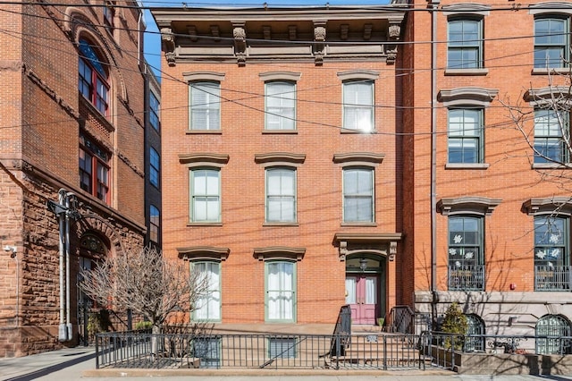 view of front of home featuring brick siding and fence