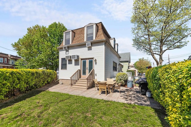 rear view of house with a lawn, mansard roof, a patio, a shingled roof, and entry steps