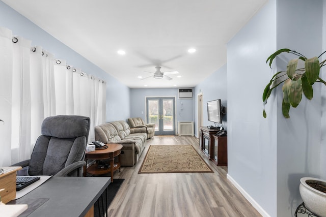 living room featuring radiator heating unit, ceiling fan, light wood-style floors, and a wall unit AC