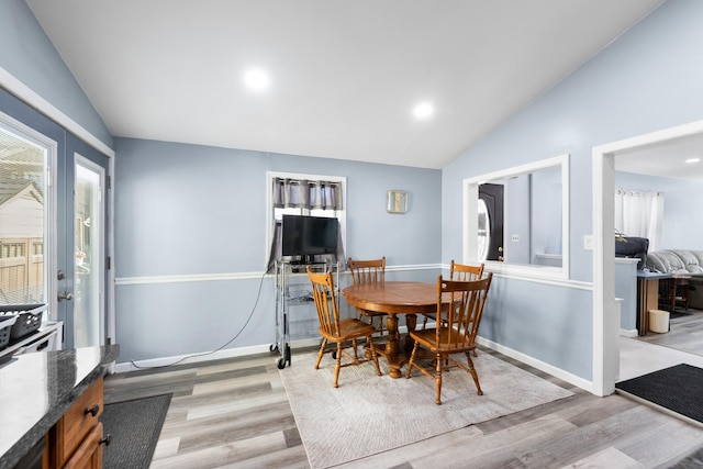 dining room with baseboards, lofted ceiling, and light wood-type flooring