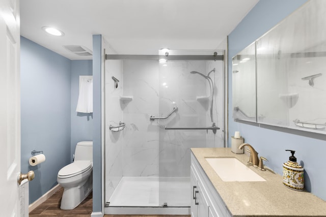 bathroom with wood finished floors, toilet, a marble finish shower, and vanity