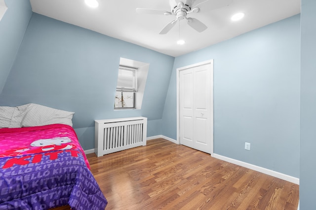 bedroom featuring a closet, radiator, wood finished floors, baseboards, and recessed lighting