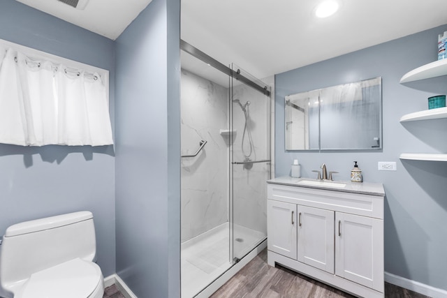 bathroom featuring wood finished floors, vanity, toilet, a marble finish shower, and recessed lighting