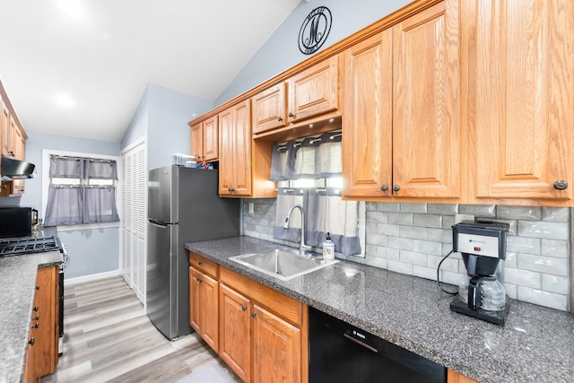 kitchen featuring dark countertops, under cabinet range hood, a sink, black appliances, and vaulted ceiling