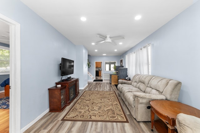 living area with baseboards, ceiling fan, a healthy amount of sunlight, and wood finished floors
