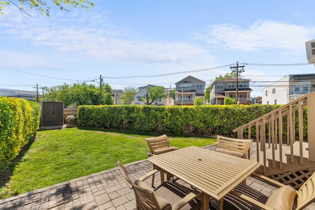 view of patio / terrace with a storage unit, an outdoor structure, a fenced backyard, and outdoor dining area