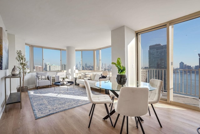 dining area featuring floor to ceiling windows, a city view, and wood finished floors