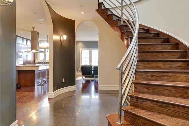 staircase featuring recessed lighting, baseboards, and arched walkways