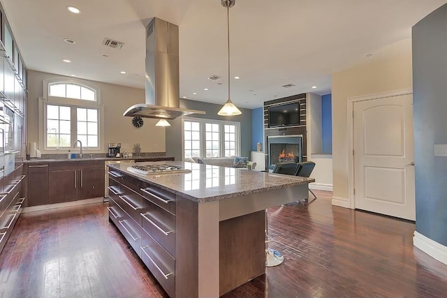 kitchen featuring visible vents, a breakfast bar, island exhaust hood, a kitchen island, and stainless steel gas cooktop