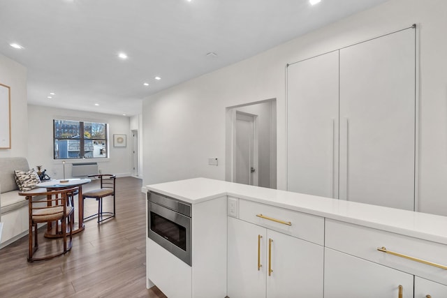 kitchen with recessed lighting, white cabinetry, light countertops, light wood finished floors, and stainless steel microwave