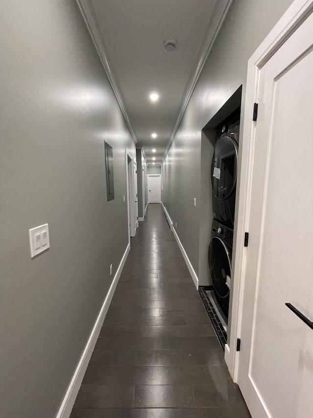 hall with baseboards, crown molding, stacked washer and clothes dryer, electric panel, and dark wood-style floors