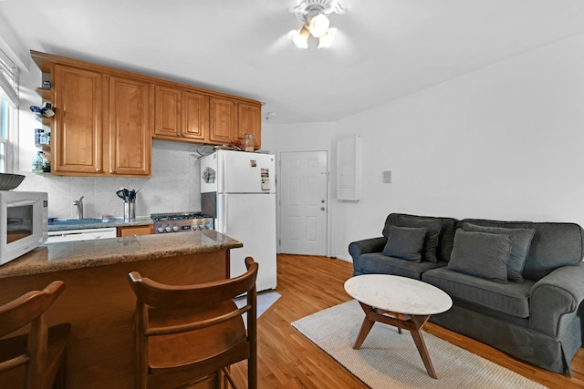 734 Adams St Unit 4B, Hoboken, NJ 07030 - kitchen featuring white appliances, a ceiling fan, tasteful backsplash, light wood finished floors, and a kitchen bar
