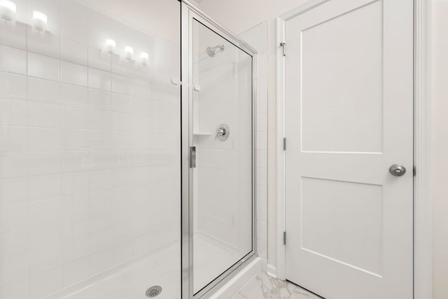 bathroom featuring a stall shower and marble look tile flooring