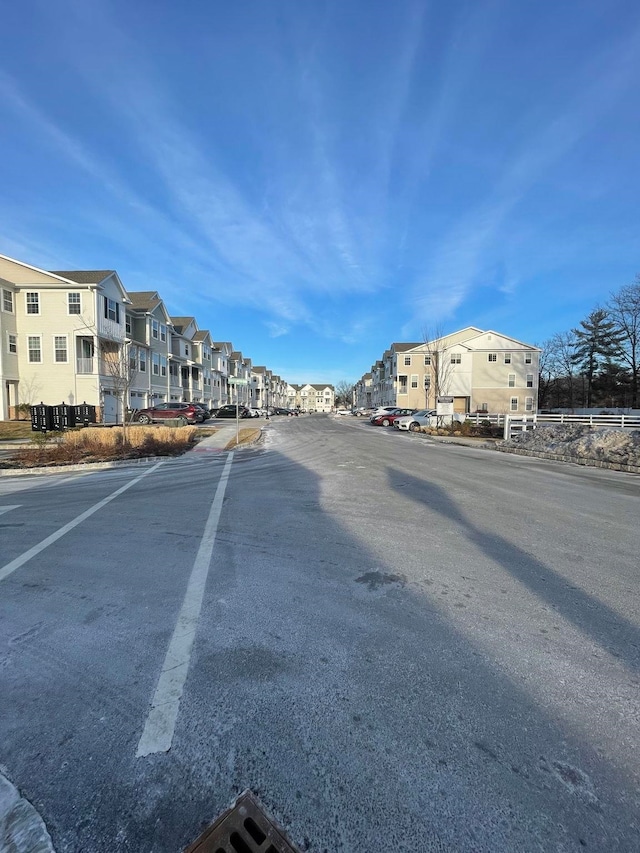 view of asphalt road with a residential view and curbs