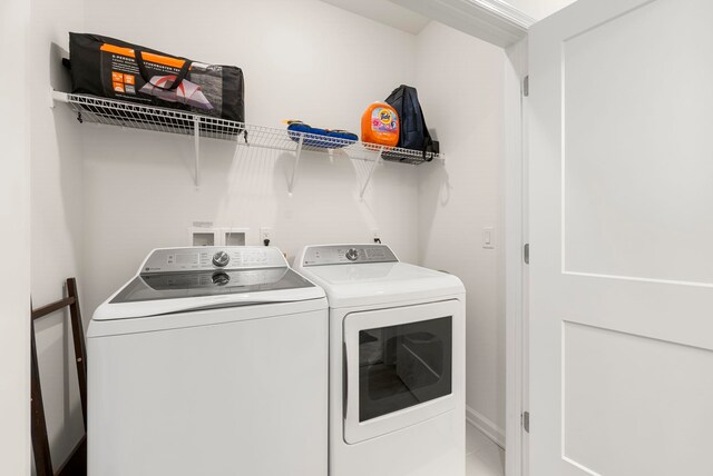 clothes washing area with washing machine and clothes dryer and baseboards