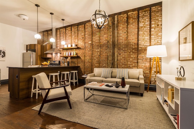 living room with dark wood-type flooring, a notable chandelier, and brick wall