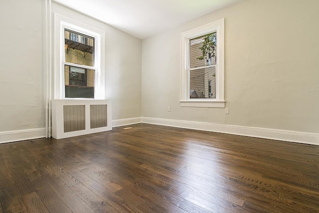 unfurnished room featuring dark wood-type flooring and radiator heating unit