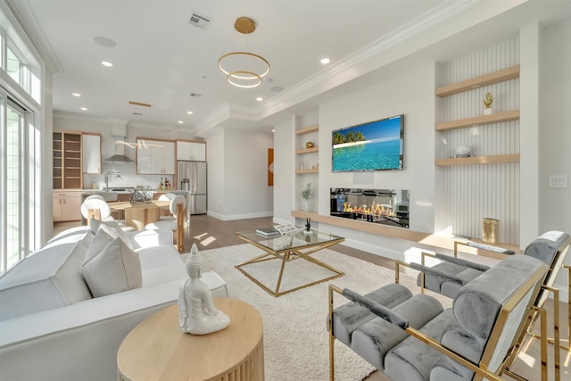 living room featuring light hardwood / wood-style floors, sink, built in features, and crown molding