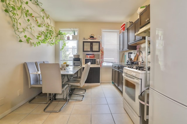 400 67th St, West New York, NJ 07093 - kitchen with white appliances, under cabinet range hood, light tile patterned floors, dark brown cabinets, and baseboards