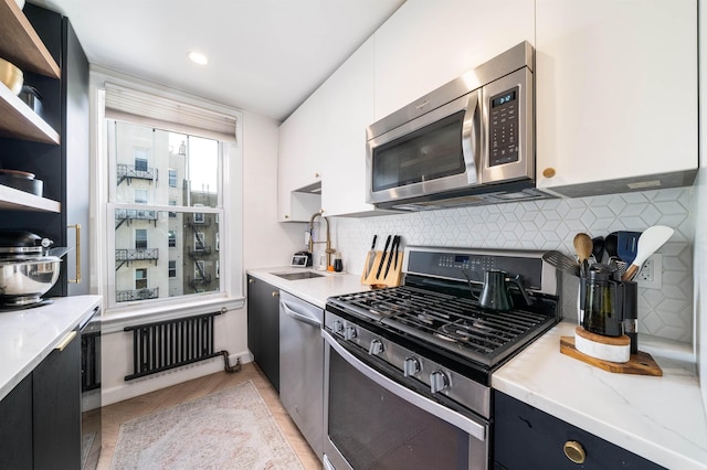 kitchen featuring decorative backsplash, appliances with stainless steel finishes, open shelves, a sink, and white cabinets