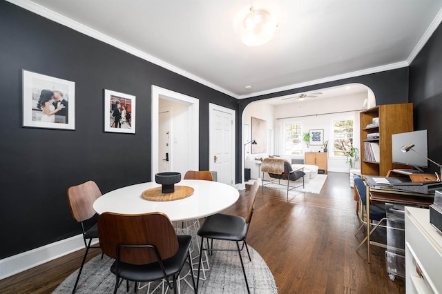 dining room with baseboards, arched walkways, a ceiling fan, and wood finished floors