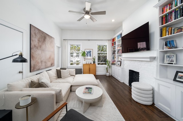living area featuring ceiling fan, a brick fireplace, dark wood finished floors, radiator heating unit, and recessed lighting