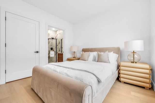 bedroom featuring ensuite bath and light wood-style flooring